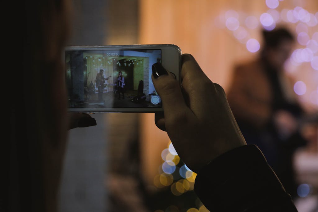 A smartphone records a live indoor music performance in a warm, festive setting.